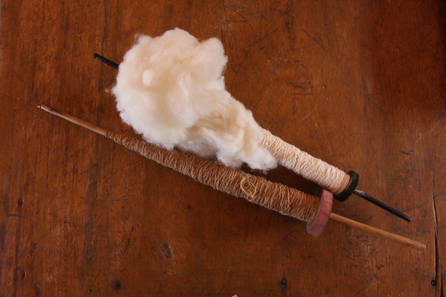 Photo of two spindles with cotton thread in white and brown colours