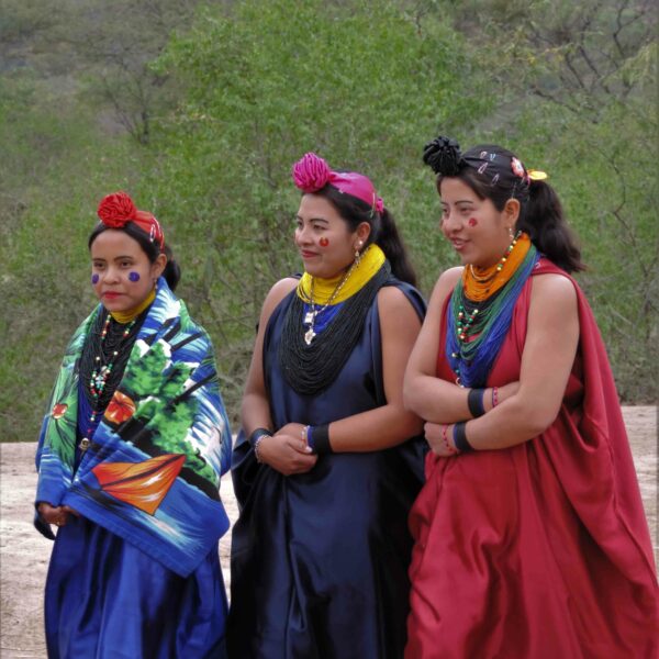 Photo of three young women dressed up ceremonially, wearing a variety of colours and head-dresses