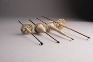 Photo of four spindles with white cotton thread